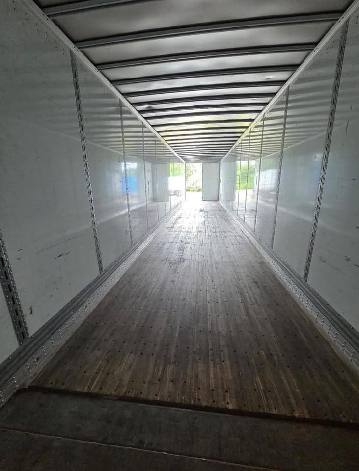 Interior of a 53-foot dry van looking toward the rear doors, showing E-track logistics rails and a hardwood floor