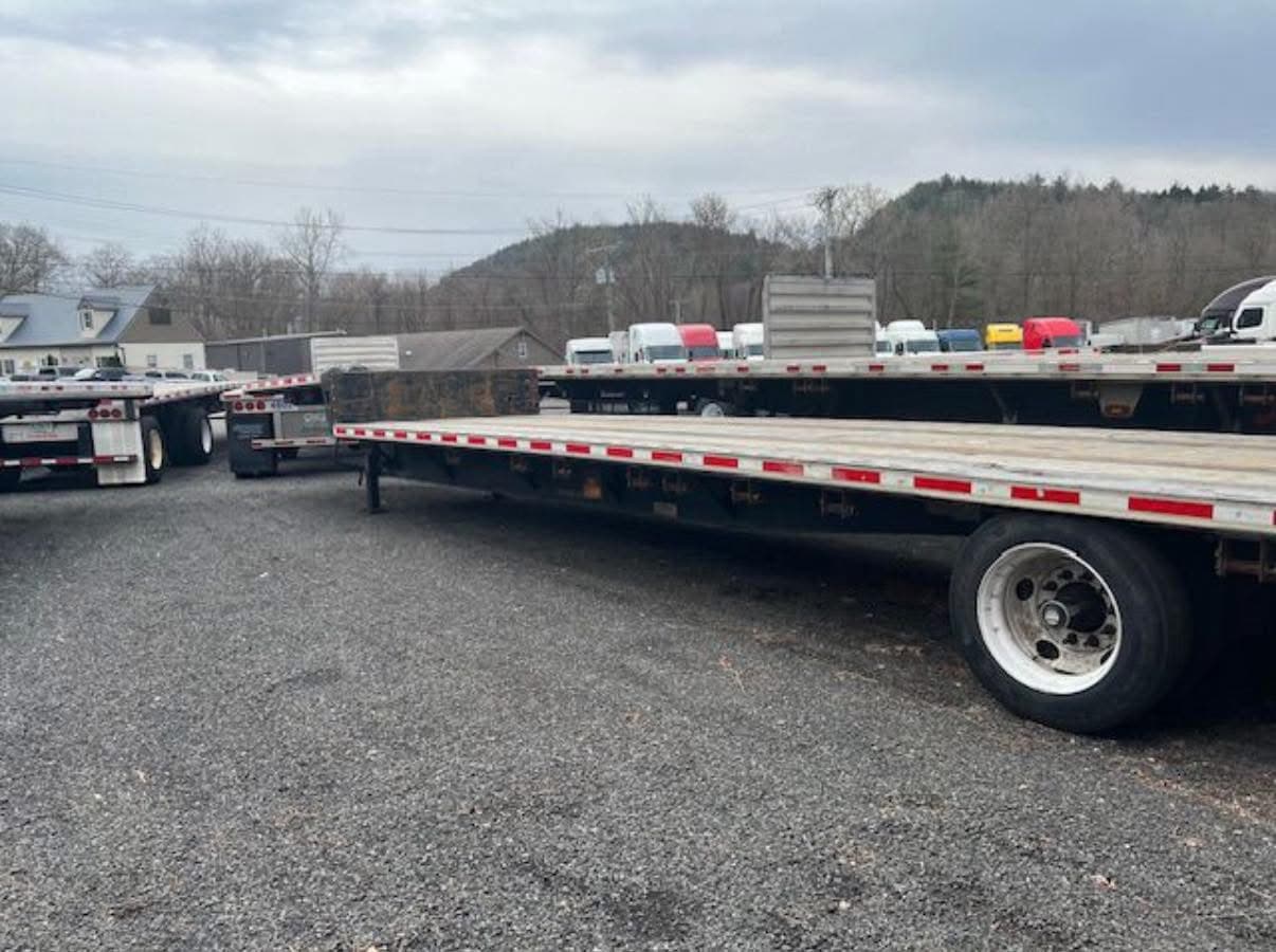 Row of 48-foot flatbed trailers staged in a yard, showing the full combination deck